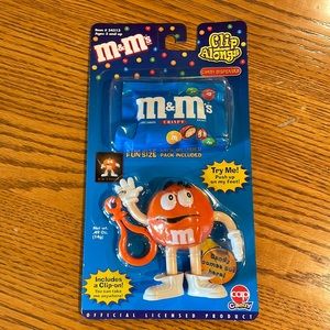 M&M’s clip along orange character. CANDY IS OLD AND SHOULD NOT BE EATEN